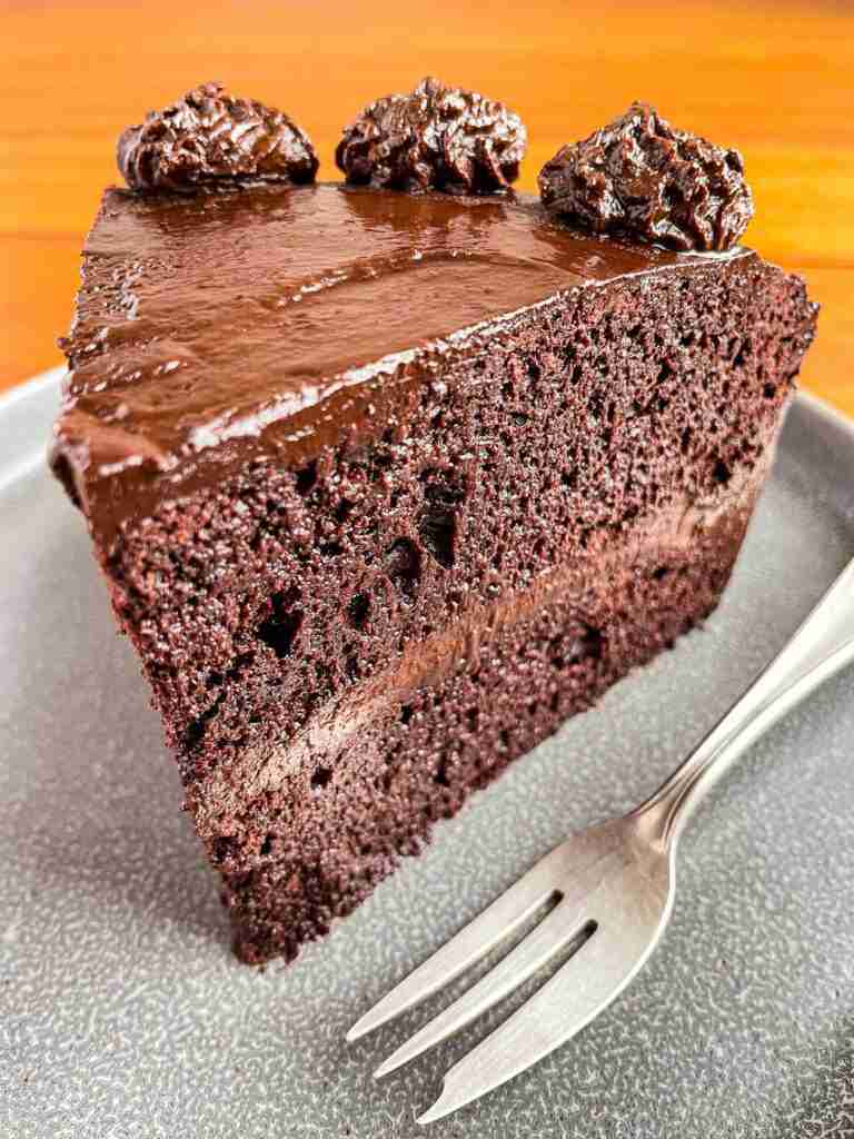 A slice of healthy chocolate ganache cake with vegan chocolate avocado frosting.