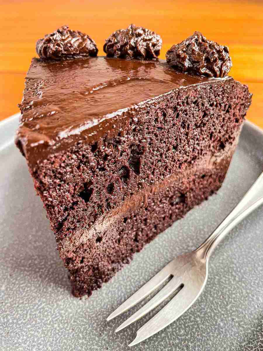 A slice of Vegan Chocolate Cake with chocolate avocado frosting.