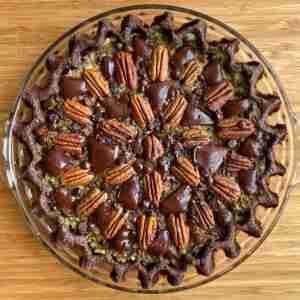 An overhead shot of a low-carb, keto chocolate chip pecan pie decorated with a pattern of sugar-free dark chocolate chunks and pecans.