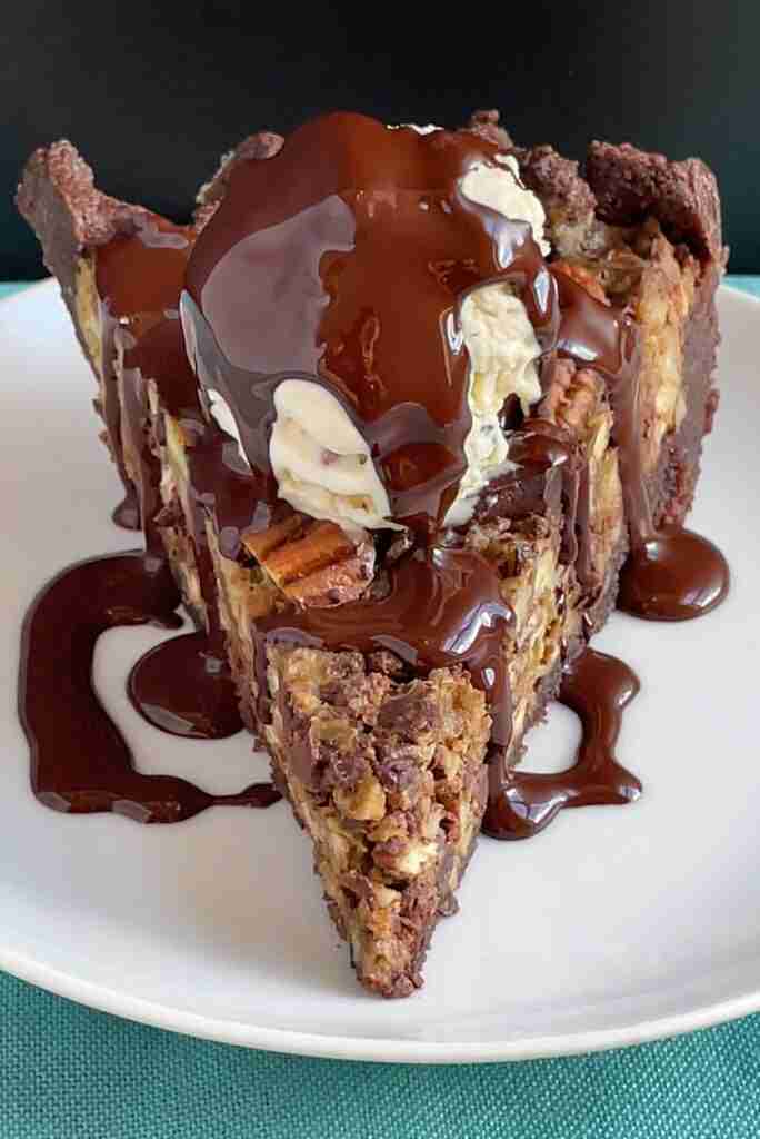 A slice of sugar-free, chocolate chip pecan pie topped with a scoop of sugar-free chocolate pecan ice cream and drizzled with melted dark chocolate – the ultimate keto chocolate pecan pie.