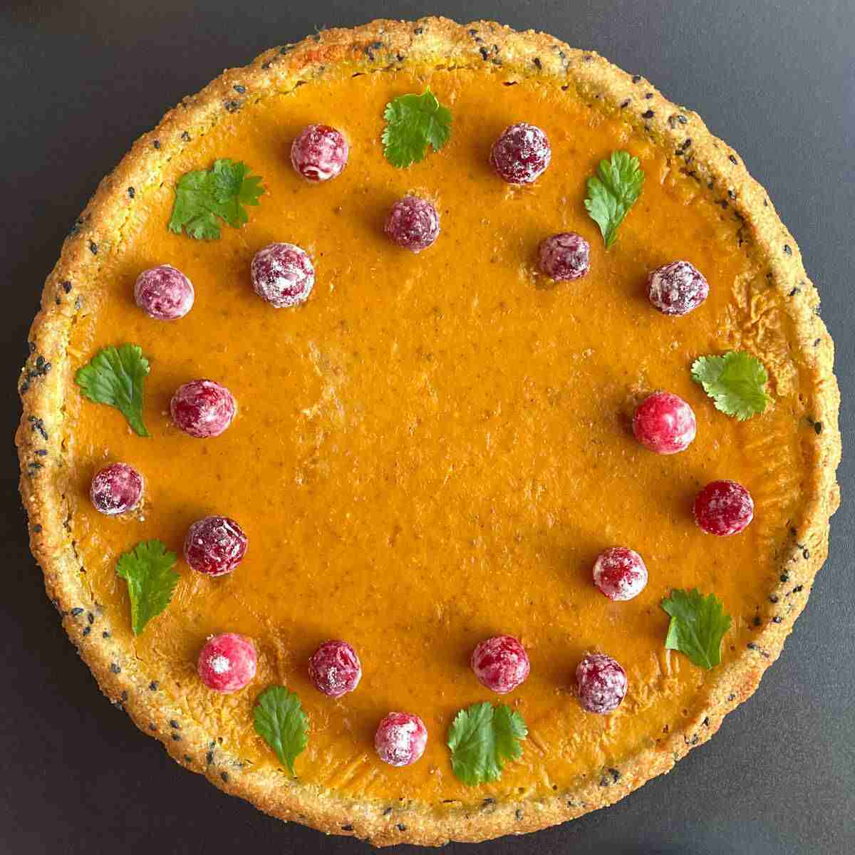 The perfect healthy pumpkin pie in a black sesame, almond flour crust, topped with sugared cranberries.