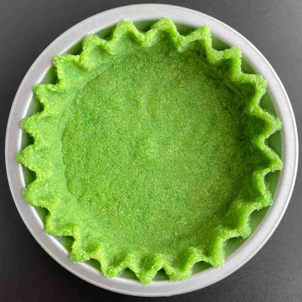 A healthy, sugar free crust, also called an almond flour pie crust that is dyed green and fluted.