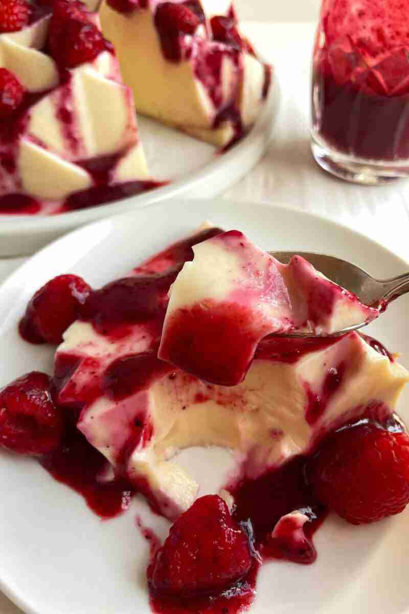 A slice of milk jello with raspberries and berry sauce.
