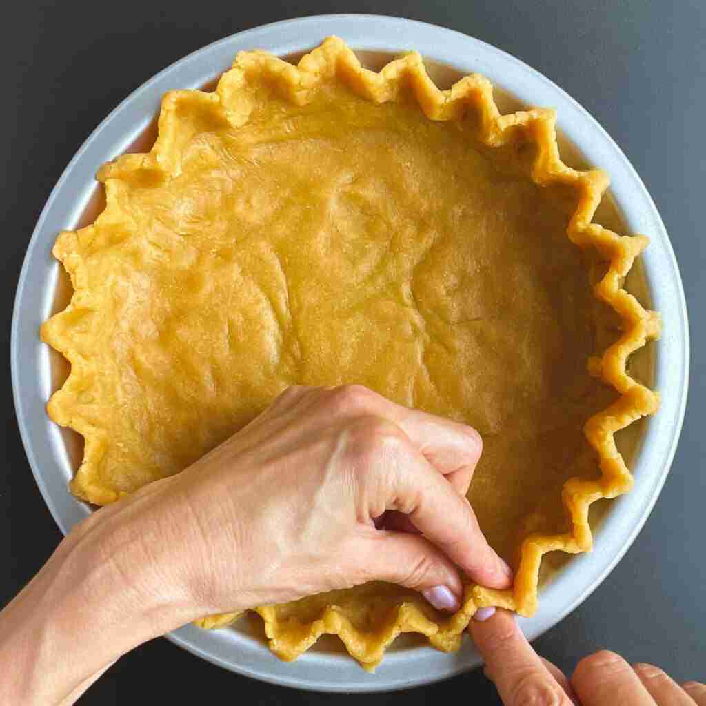 A step in a chickpea dessert recipe: how to flute the edges of the pie.