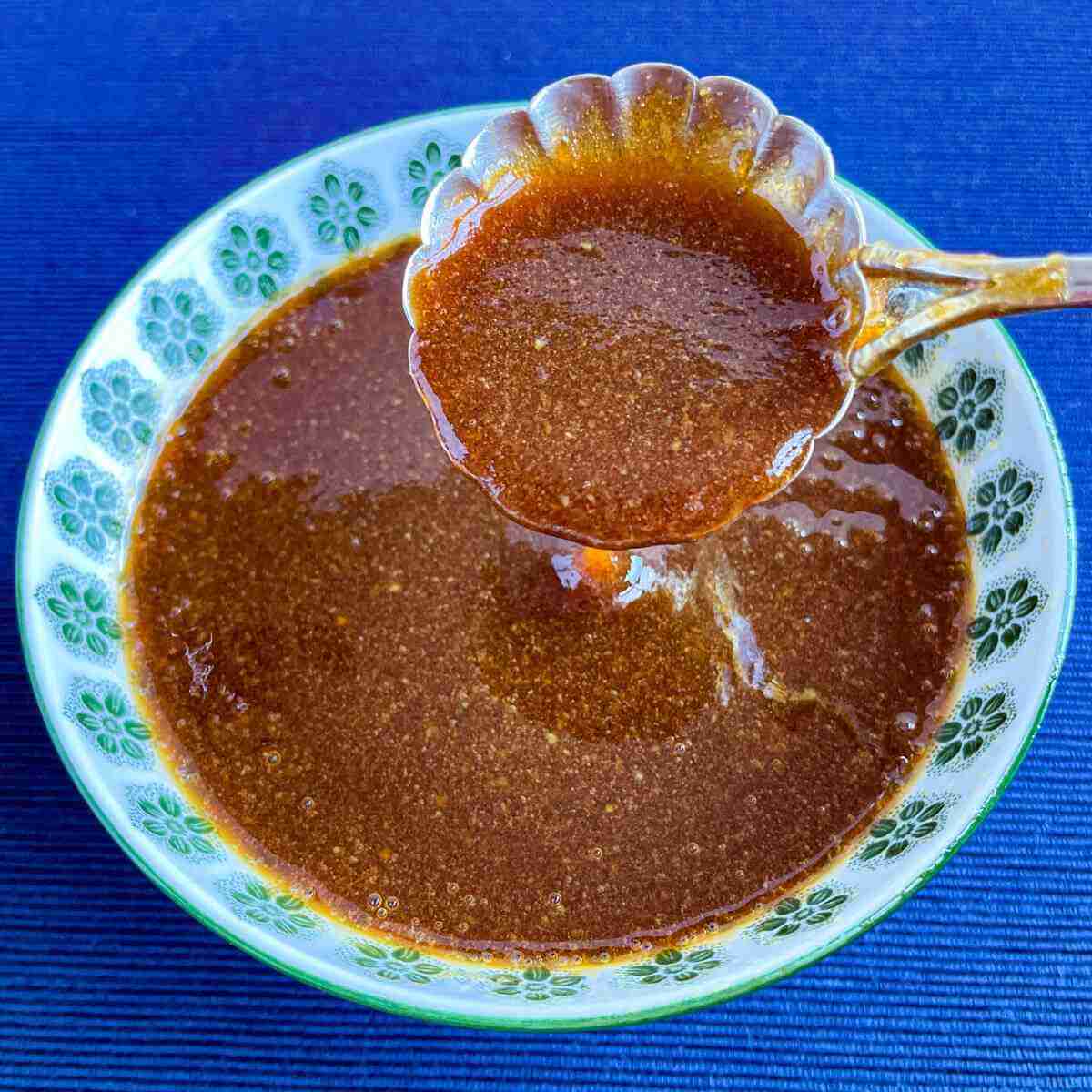 A spoonful of healthier homemade teriyaki sauce made with monk fruit and held over a small Japanese bowl.