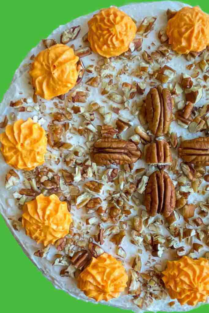 Sugar free healthy carrot cake with keto cream cheese frosting and pecans on top.