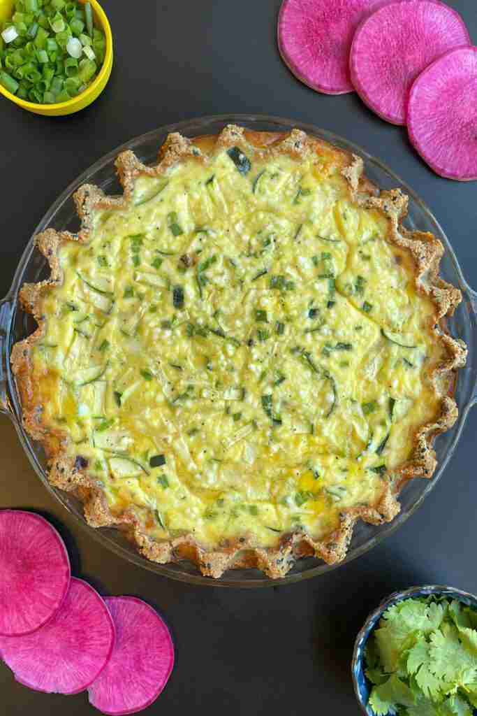 A baked low carb Japanese quiche, also called Salmon Teriyaki Keto Quiche, with green onions and magenta watermelon radishes on the side.