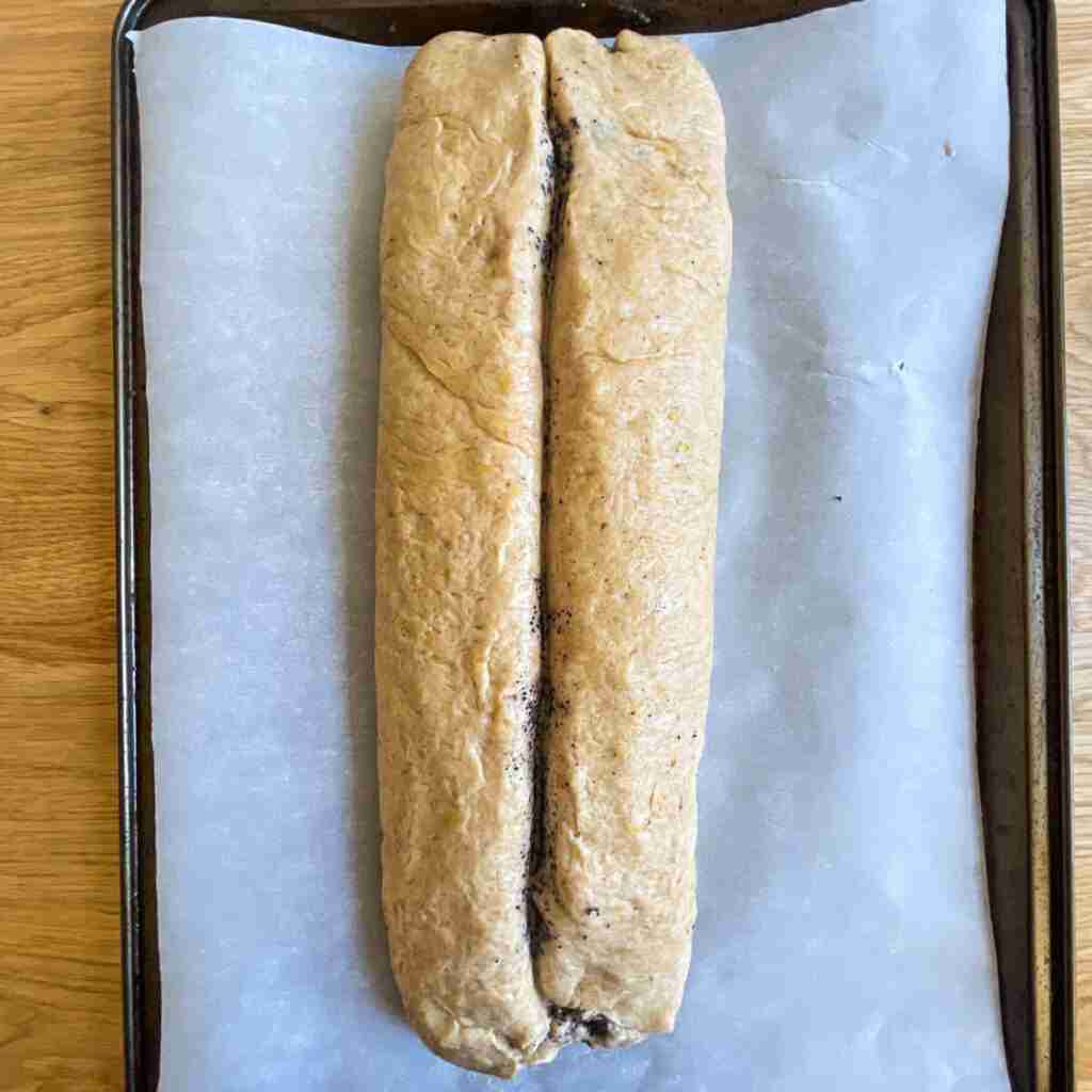 Fully rolled and on parchment paper on a baking sheet.