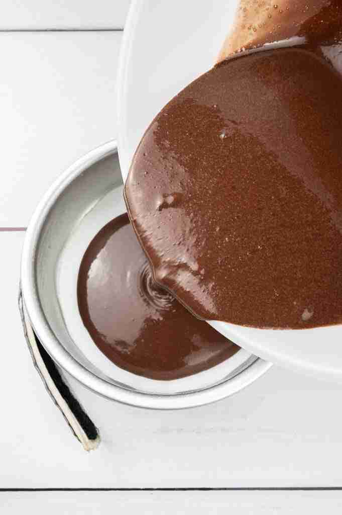 A step in this recipe: Pouring the batter into cake pans to make black forest cake.