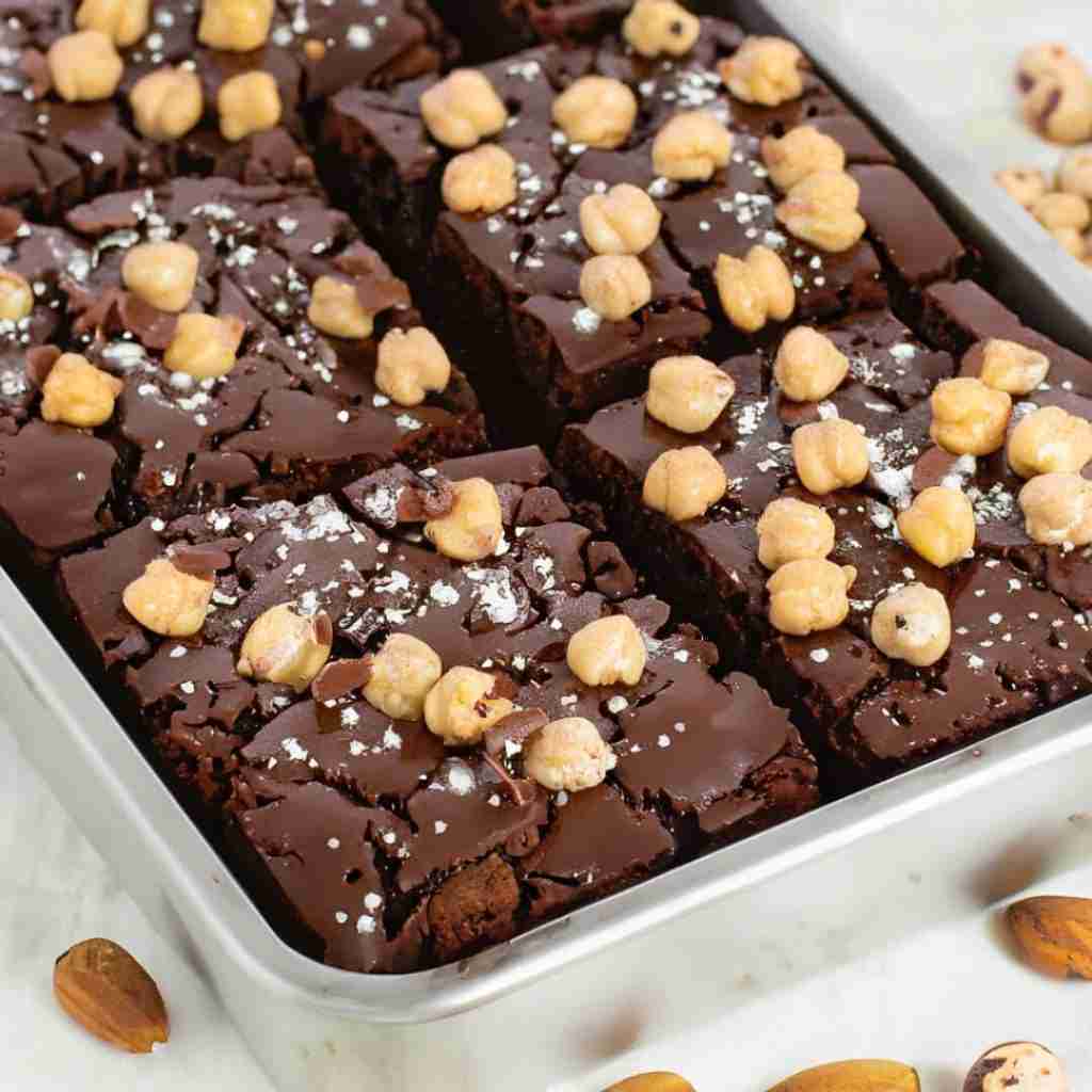 Chickpea brownies in a baking pan topped with chickpeas and powdered monk fruit sweetener.
