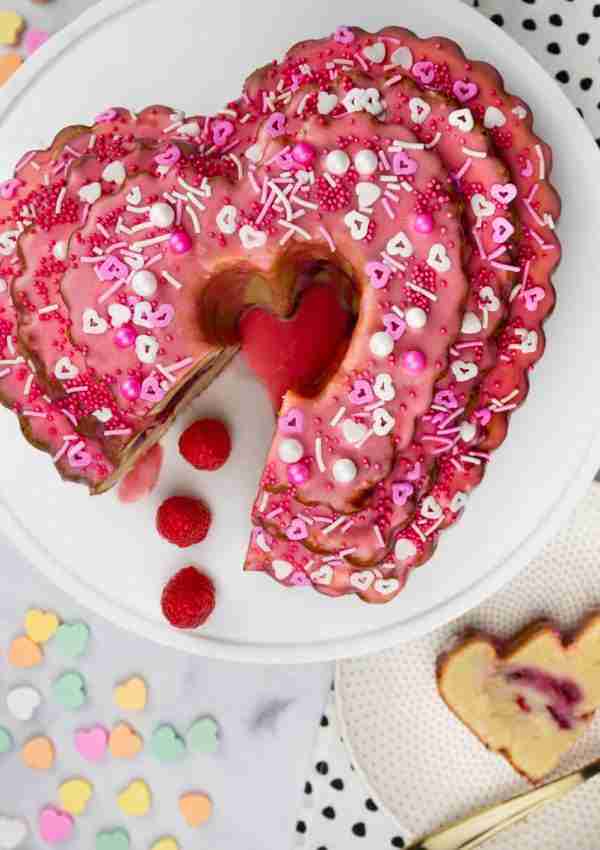 A raspberry swirl bundt cake decorated for Valentine's Day with a slice on the side.