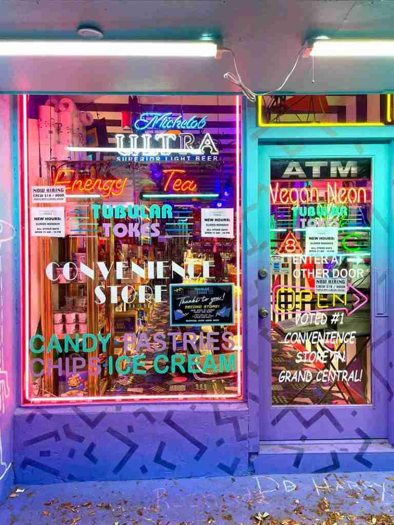 Convenience store with colorful neon signs on the door and window in the arty Grand Central District.