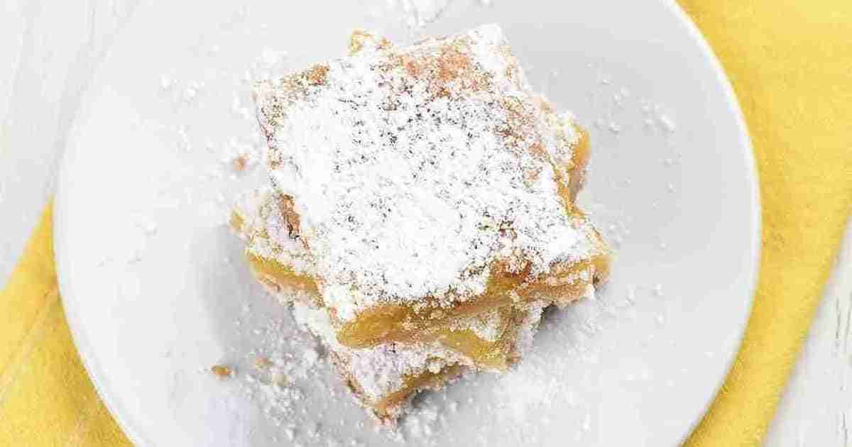 Gluten-free lemon bars topped with powdered monk fruit on a plate.