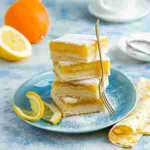 The baked keto lemon-orange almond flour bars recipe: A stack of 4 bars with a lemon and orange in background.