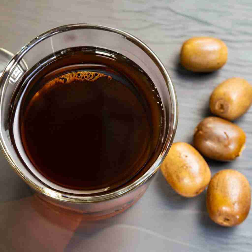 Homemade monk fruit tea, also called luo han guo tea, in a cup made from dried monk fruit and some monk fruit next to it.