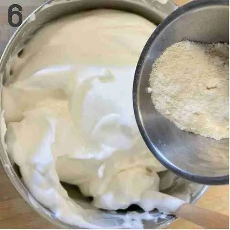 A step in the recipe: Sift the almond flour into the soft, fluffy egg whites.