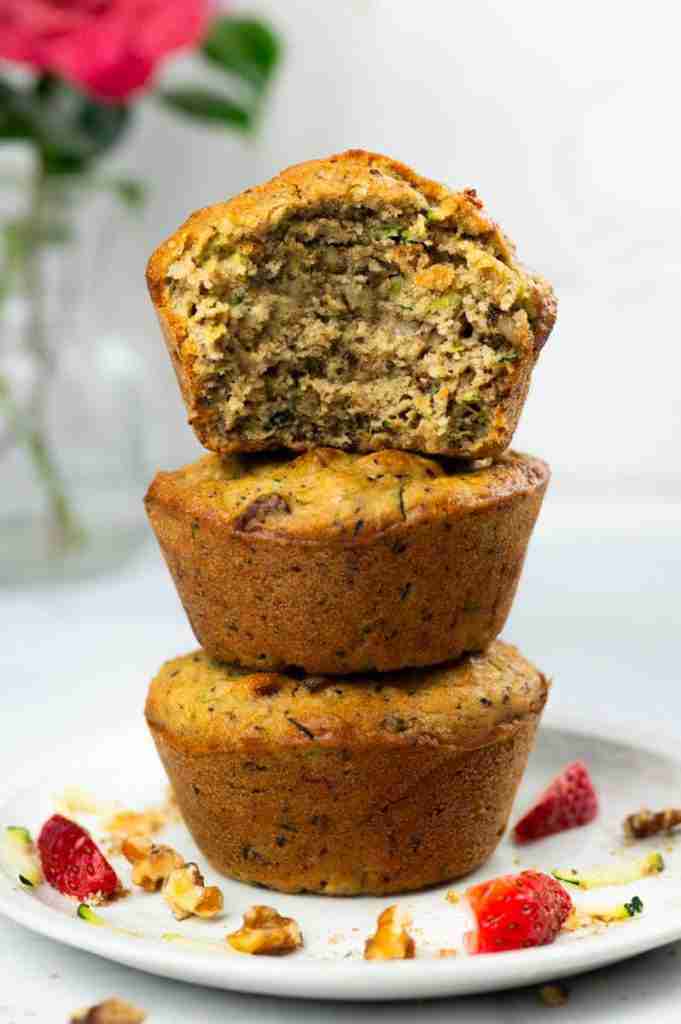 Three protein zucchini muffins stacked on a plate.