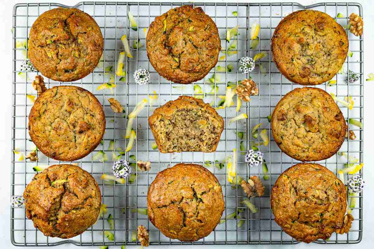 Protein zucchini muffins on a cooling rack and one is cut open so you can see inside.