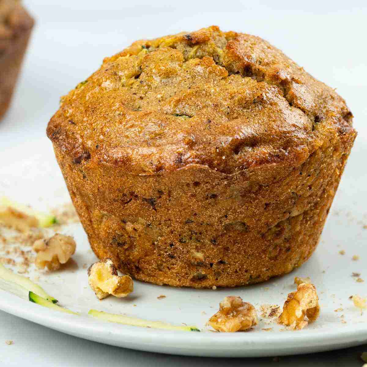 A single healthy, nutritious protein zucchini muffin on a plate.