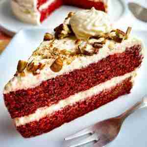 A slice of cake from my sugar free red velvet cake recipe. This keto red velvet cake is topped with diabetic cream cheese frosting and pecans.