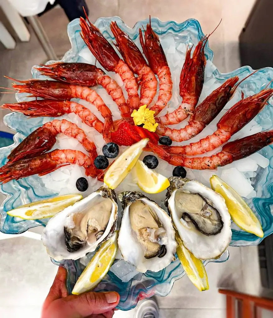 Raw seafood: prawns, oysters, with lemon slices and a sprinkling of blueberries at one of the best restaurants el cabanyal valencia.
