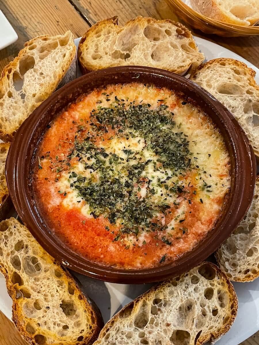 Baked provolone cheese with tomato, oregano and toasted bread at La Batisfera in Canyamelar, Valencia, Spain.