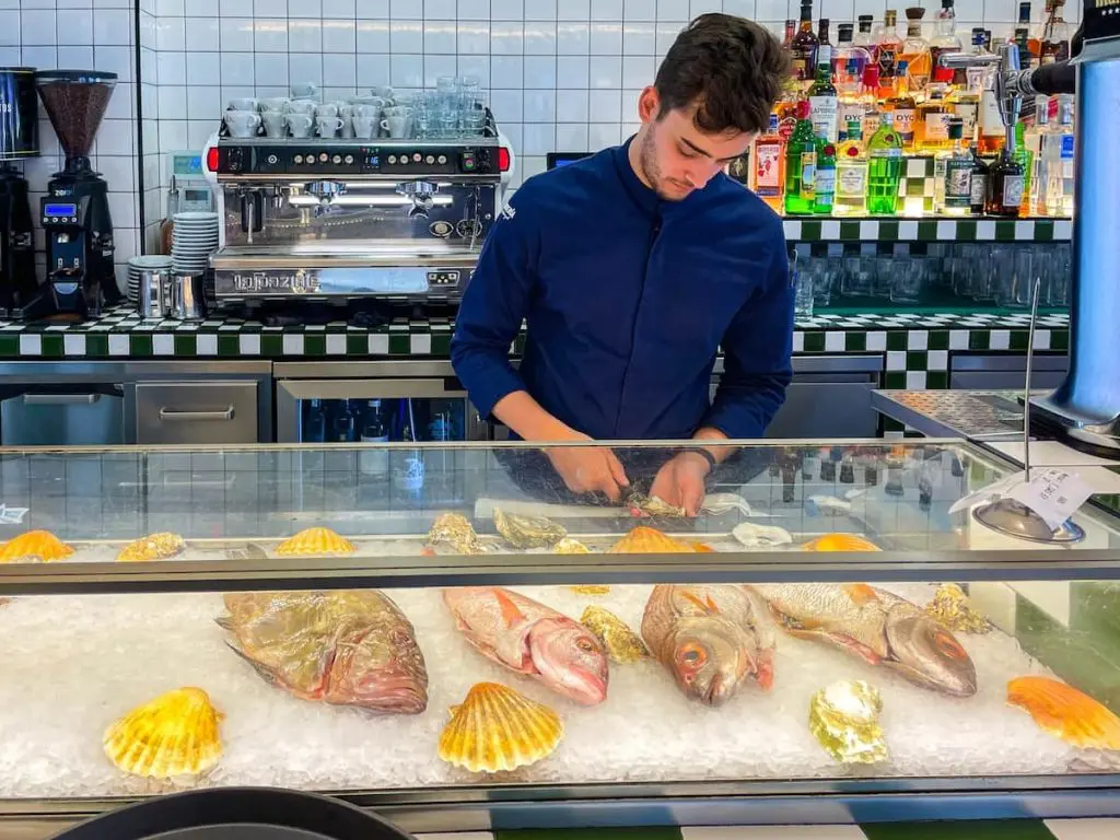 A seafood chef prepares a dish behind the seafood counter at La Sastrería Restaurant in the Cabanyal, Valencia.