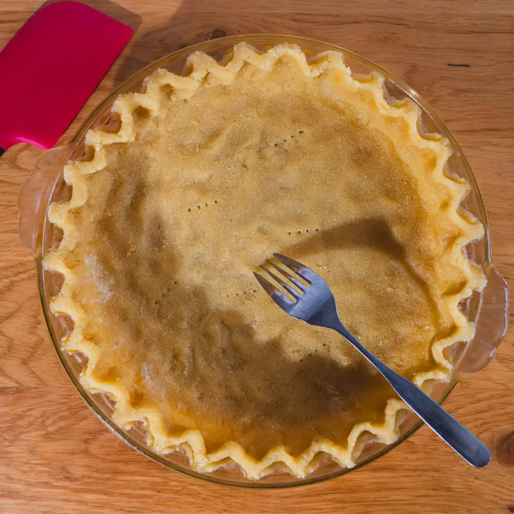 A step in the keto recipe: Using a fork to prick holes in the bottom of the unbaked tart shell, so it doesn't bubble up during baking.