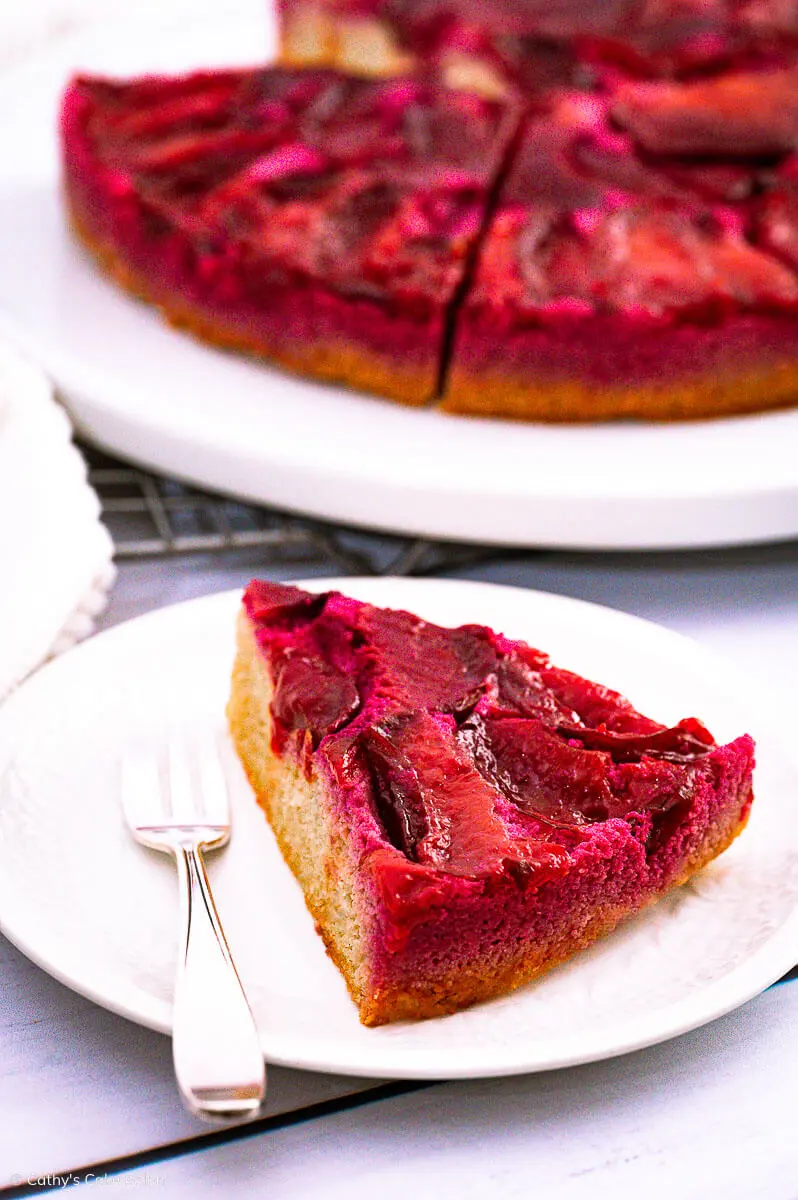 A slice of plum upside down cake and the keto plum cake in the background.