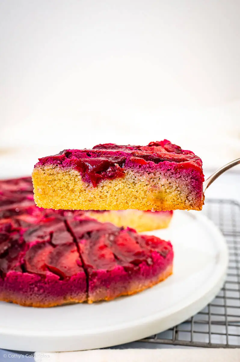 The result of this keto plum cake recipe: A slice of plum upside down cake hovering on a cake server above the sugar free cake.
