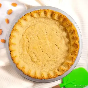 A baked almond flour vegan pie crust with crimped edges in an aluminum USA pie pan.