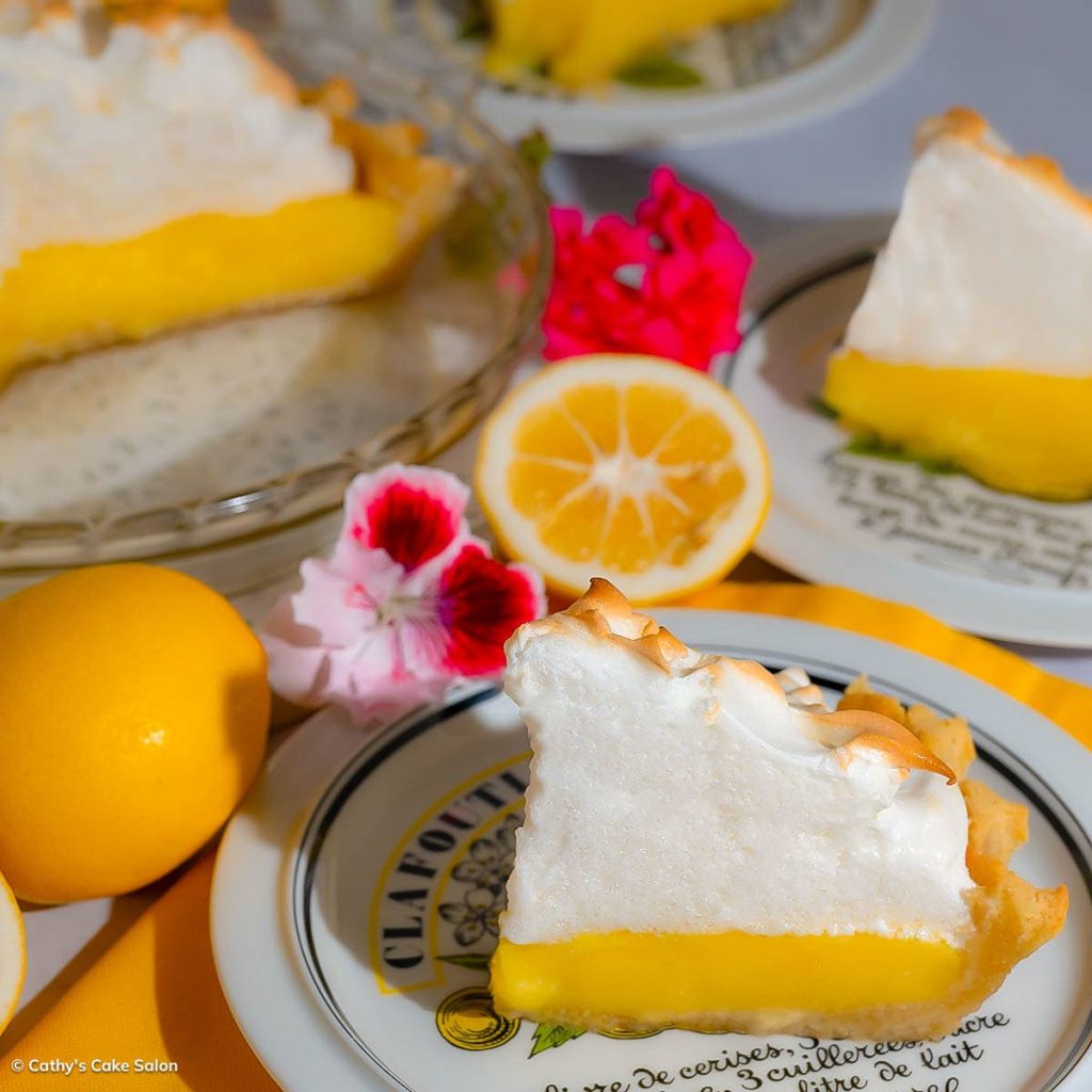 A slice of diabetic, gluten free lemon meringue pie on a table with more slices and the sliced keto pie in the background.