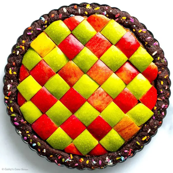 Gluten free peanut butter pie in a keto chocolate pie crust topped with a checkered geometric pattern consisting of red and green apples.