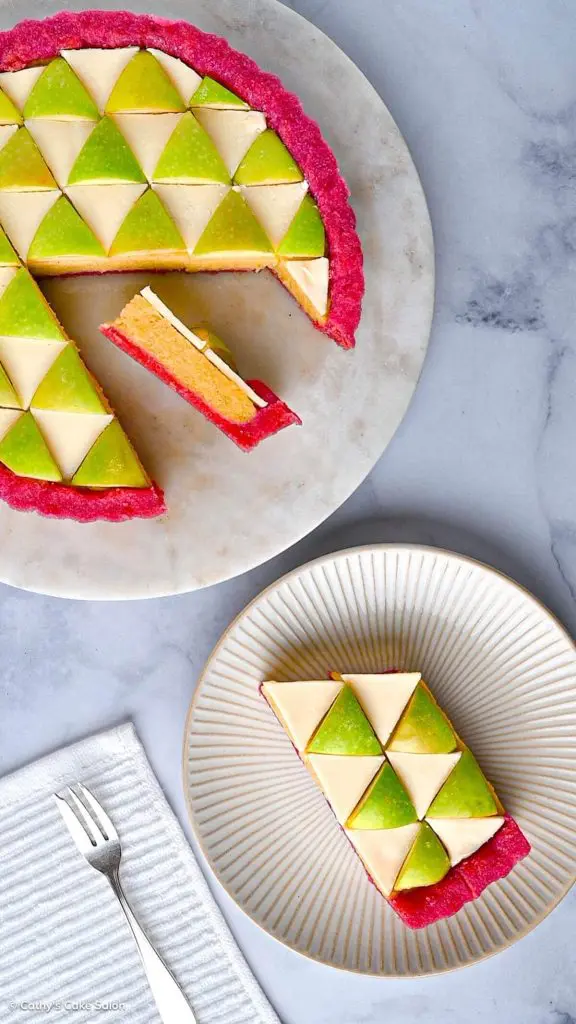 The apple tart in a dragon fruit pie crust next to a slice of apple tart topped with white chocolate and apples.