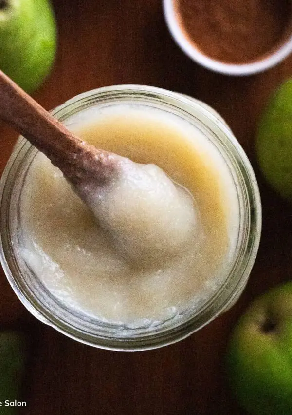 A spoon in a jar of unsweetened pear sauce.