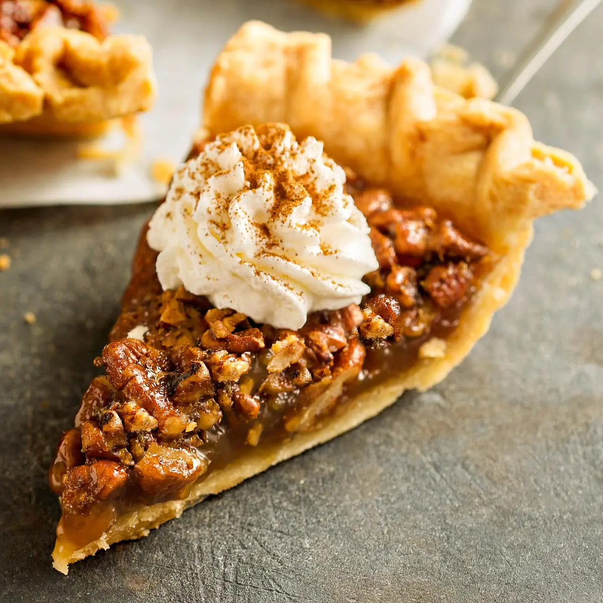 A slice of low sugar pecan pie topped with sugar free whipped cream.