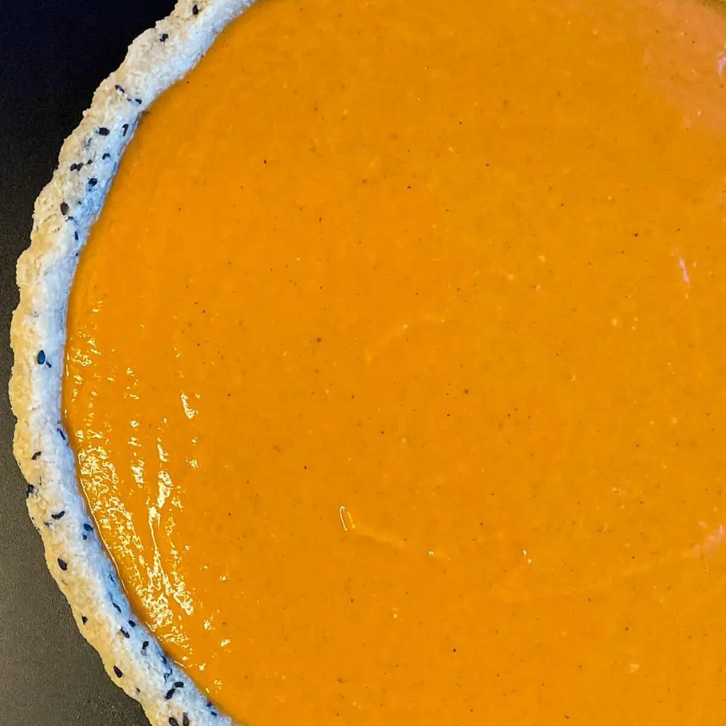 A step in the recipe: Pour the healthy sugar free pumpkin tart filling into an almond flour tart crust with black sesames.