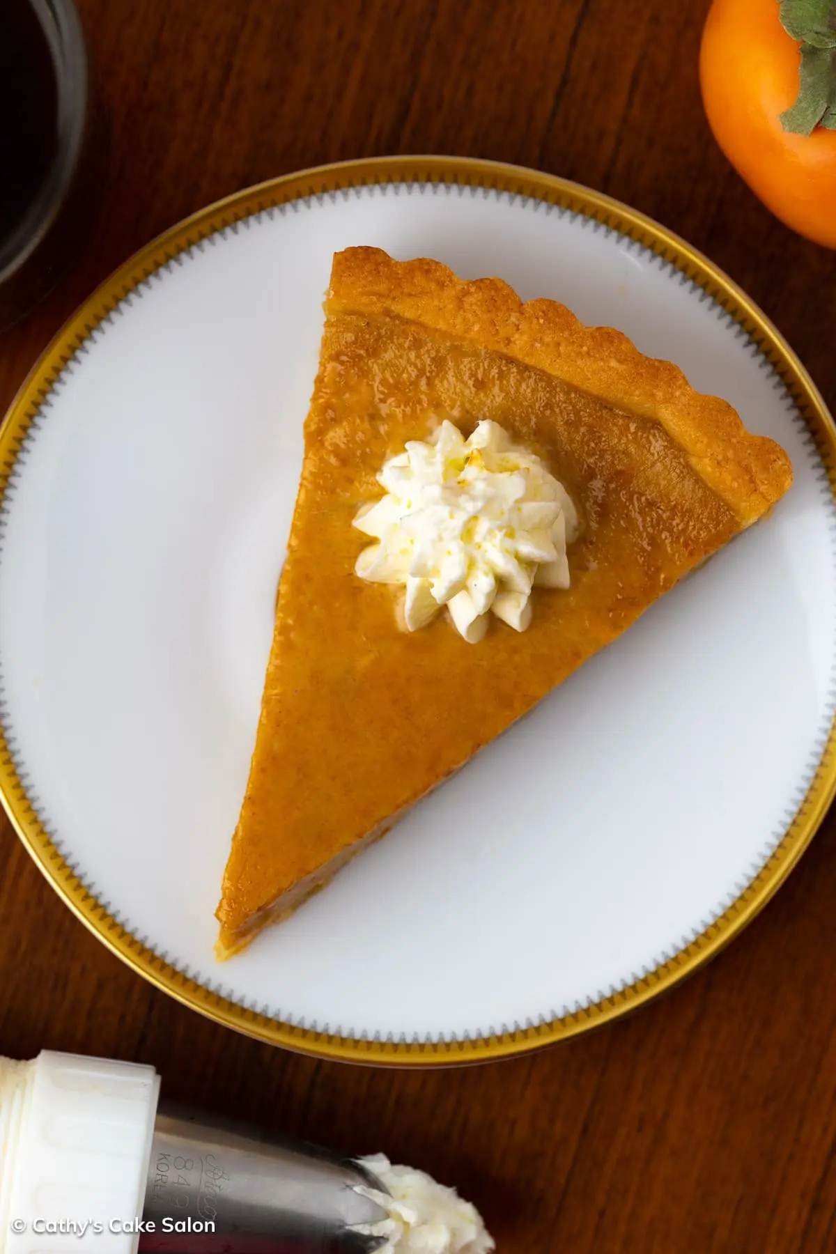 A slice of homemade persimmon tart topped with whipped cream in an almond flour tart crust.