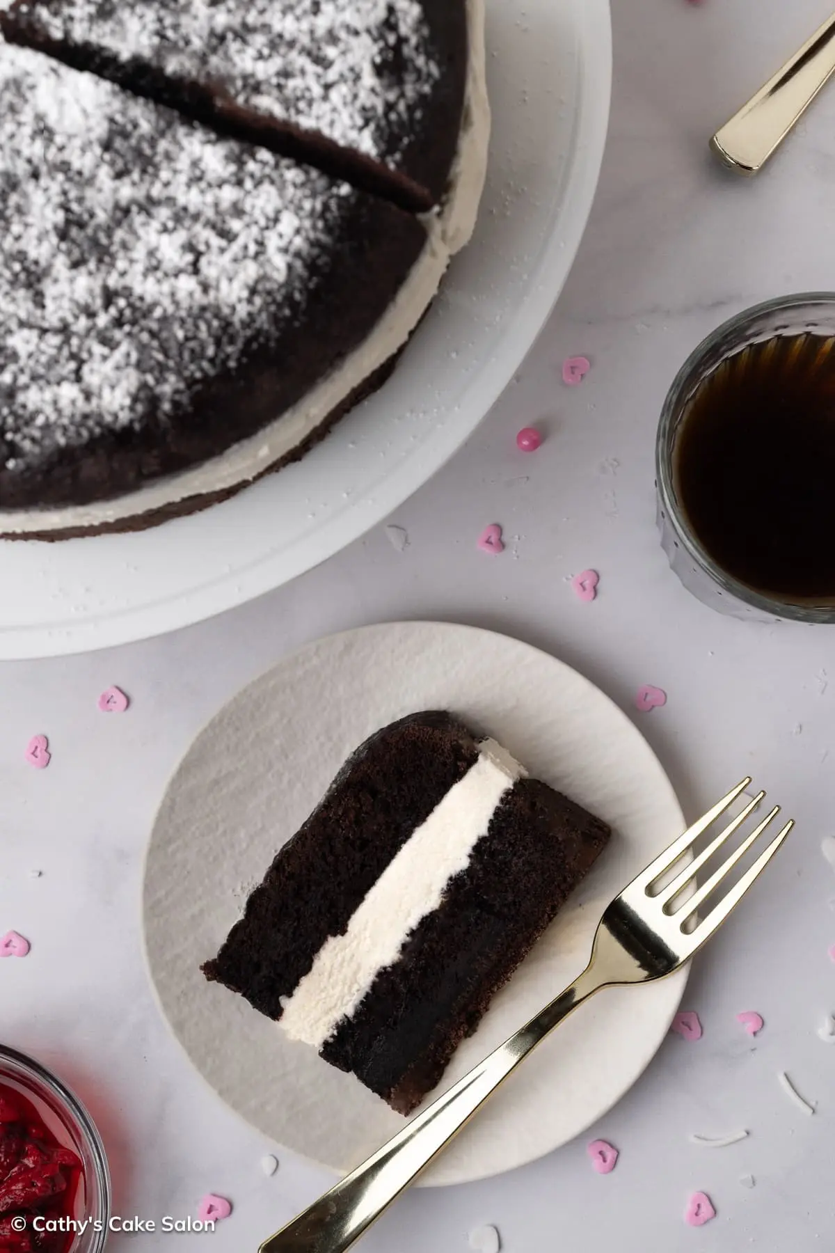 A slice of homemade Suzy Q cake with a marshmallow buttercream filling. And the whole cake in the background.