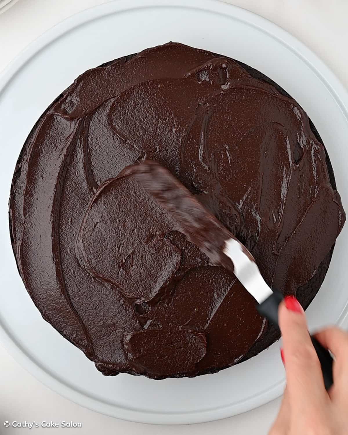 A step in the recipe: Brushing the top of the keto cake with monk fruit sweetened dark chocolate avocado frosting.