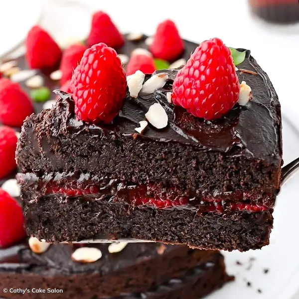 A slice of keto chocolate raspberry cake topped with almond slivers and fresh raspberries.