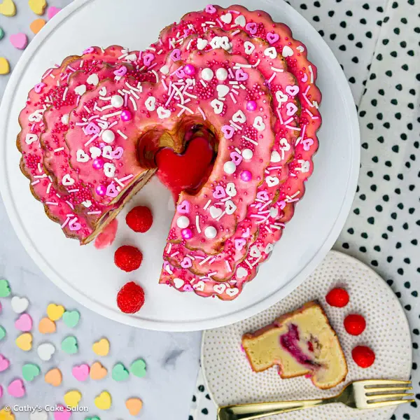 A raspberry swirl bundt cake with fresh raspberries and white and pink Valentine's Day sprinkles.
