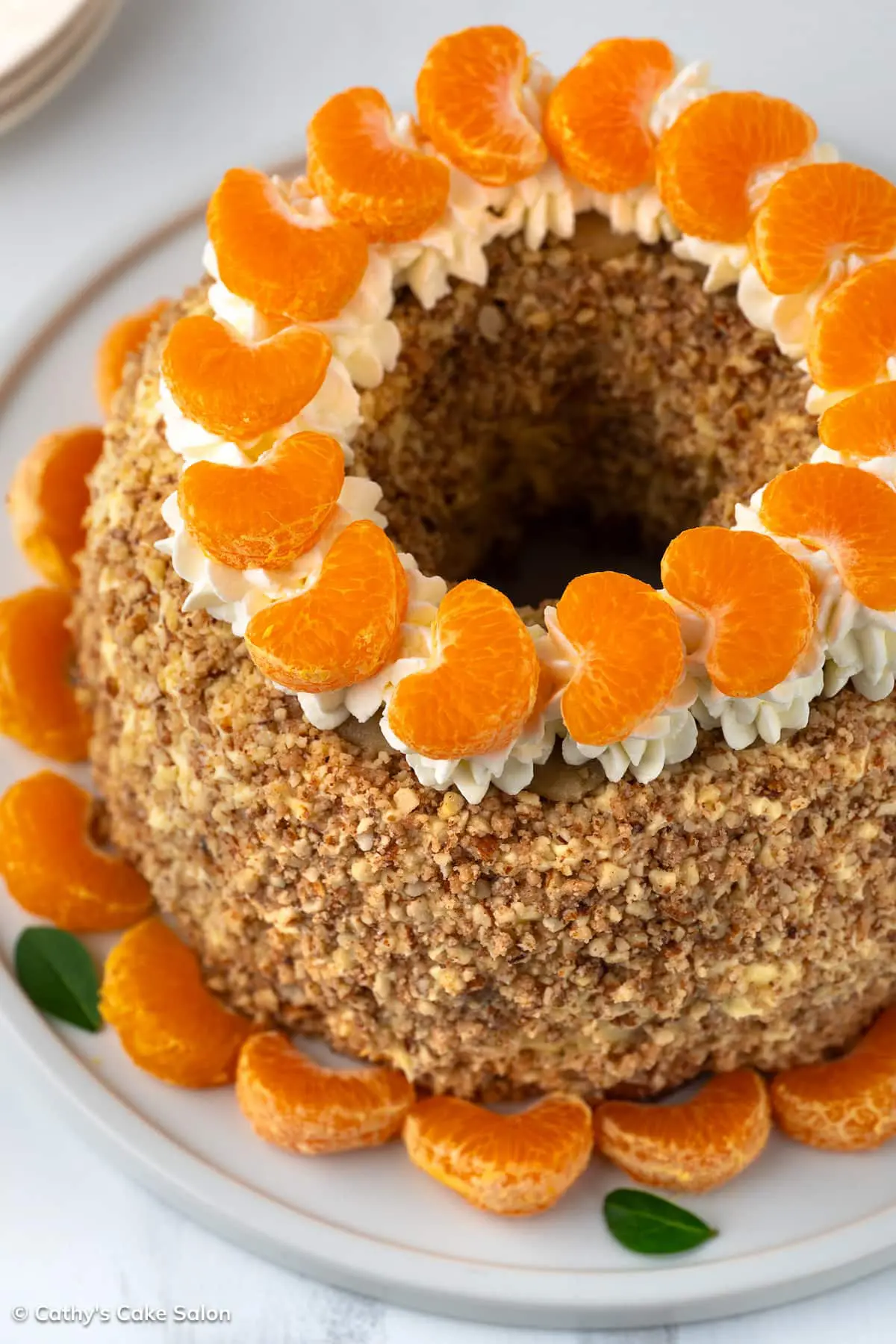 The result of this Grand Marnier whipped cream recipe: a cake topped with the orange liqueur which features cognac. Mandarins dot the whipped cream topping.