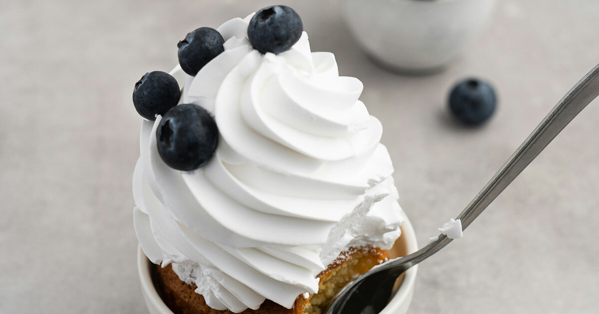 Keto whipped cream topping on a low-carb muffin with blueberries.