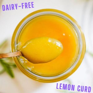 Sugar free, dairy free lemon curd filling in a glass jar with a spoon plunged into the thick curd.