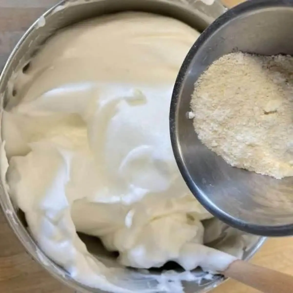 A step in the recipe: Sift the almond flour into the meringue and gently mix.