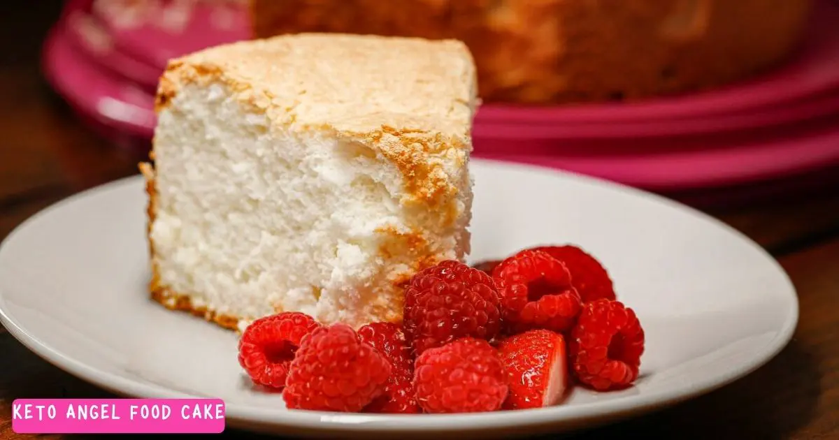 A slice of keto angel food cake on a plate served with low carb red raspberries.
