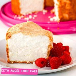 The result of this keto angel food cake recipe: A slice of low carb angel food cake on a plate served with raspberries and the gluten free angel food cake in the background.