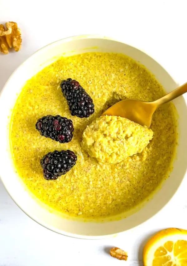 This anti-inflammatory turmeric lemon overnight oats recipe is pictured here in a bowl and topped with fresh berries.