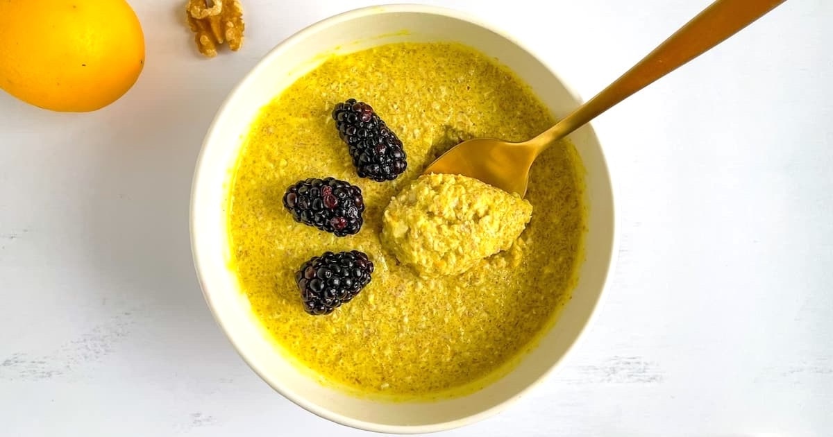 Turmeric lemon overnight oats in a bowl topped with fresh blackberries: An anti-inflammatory breakfast that also promotes glowing skin.